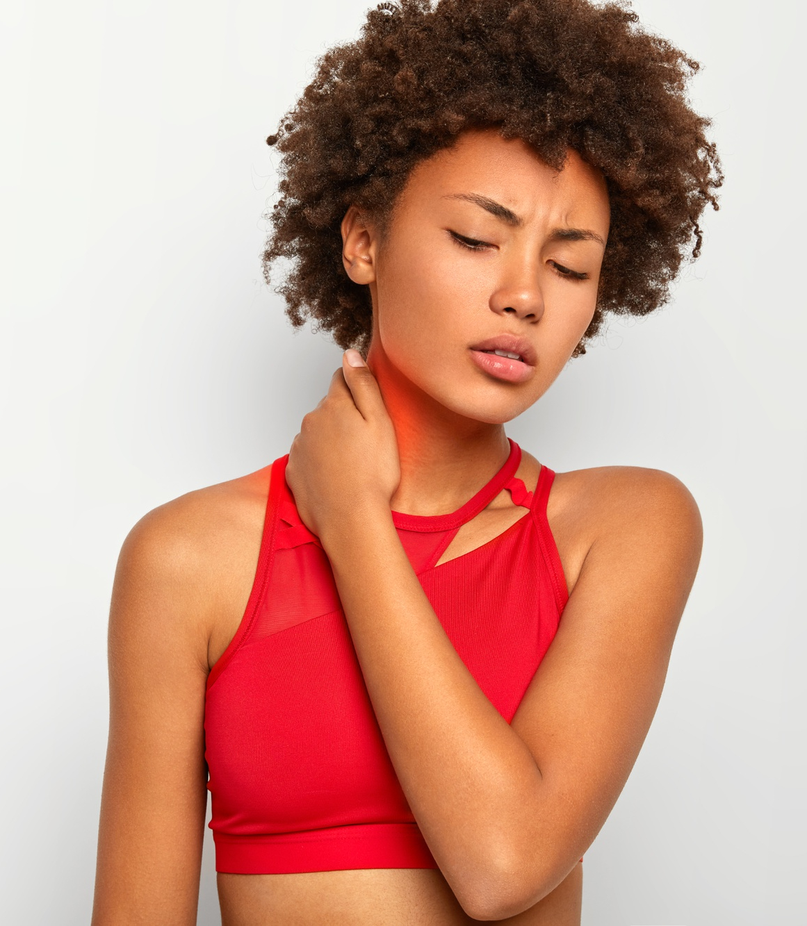 tired-curly-young-woman-touches-neck-keeps-eyes-closed-wears-red-top-tilts-head-being-exhausted-poses-agaist-white-backround-your-promotional-content.png